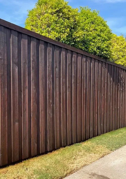 A long cedar fence finished in a dark stain